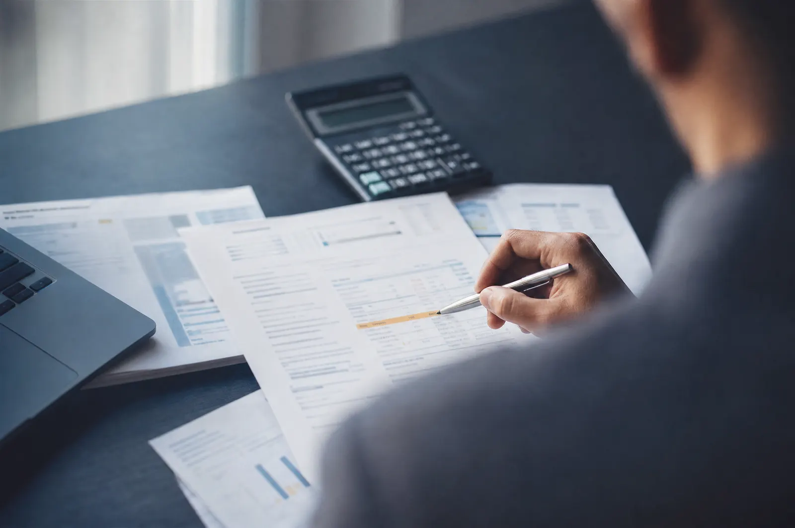 Factures d'énergie et tableau de décomposition des coûts posés sur un bureau, un stylo sur une ligne surlignée, à côté d'une calculatrice.